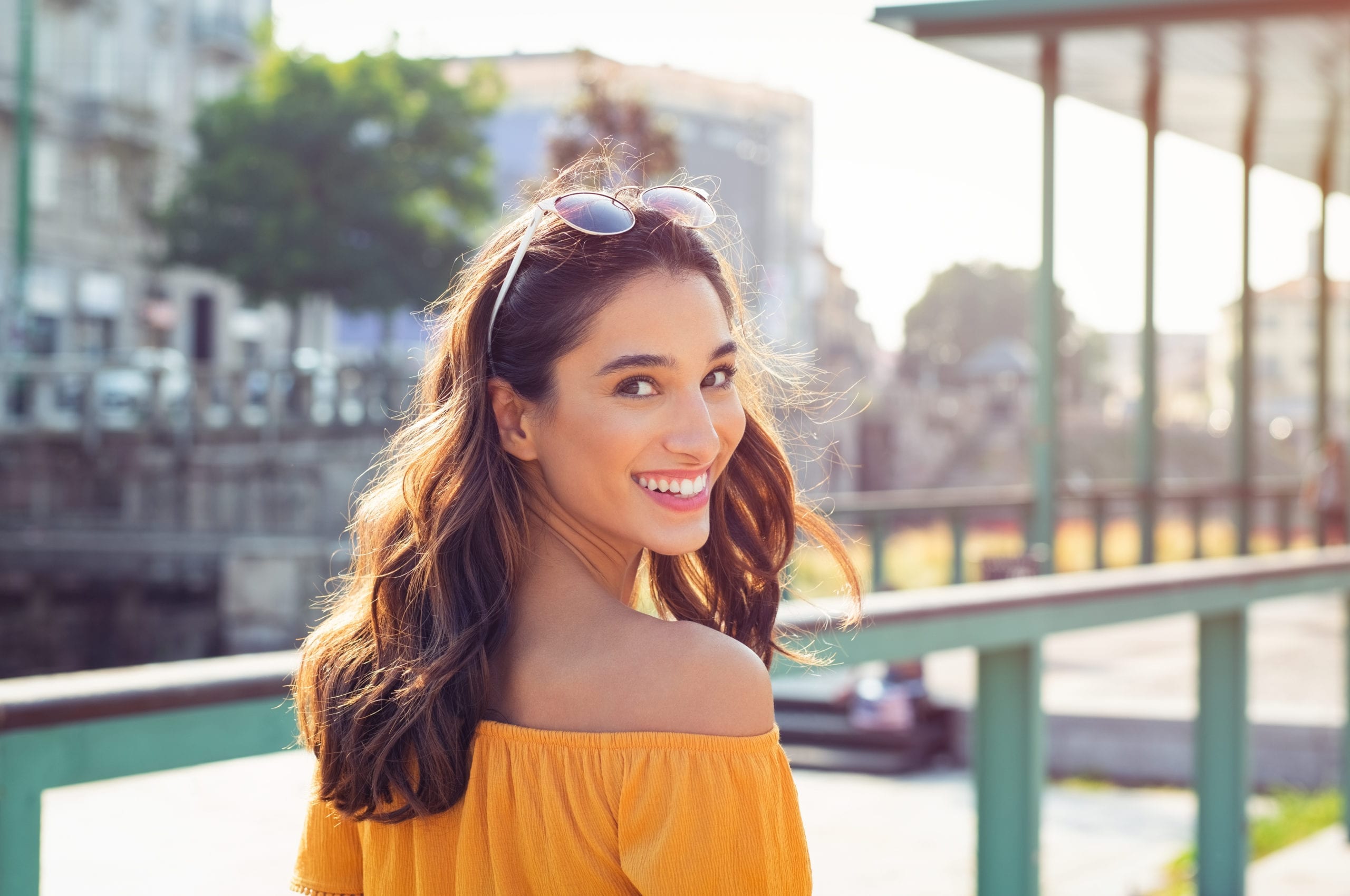 Happy latin woman looking behind while walking on street. Beauti