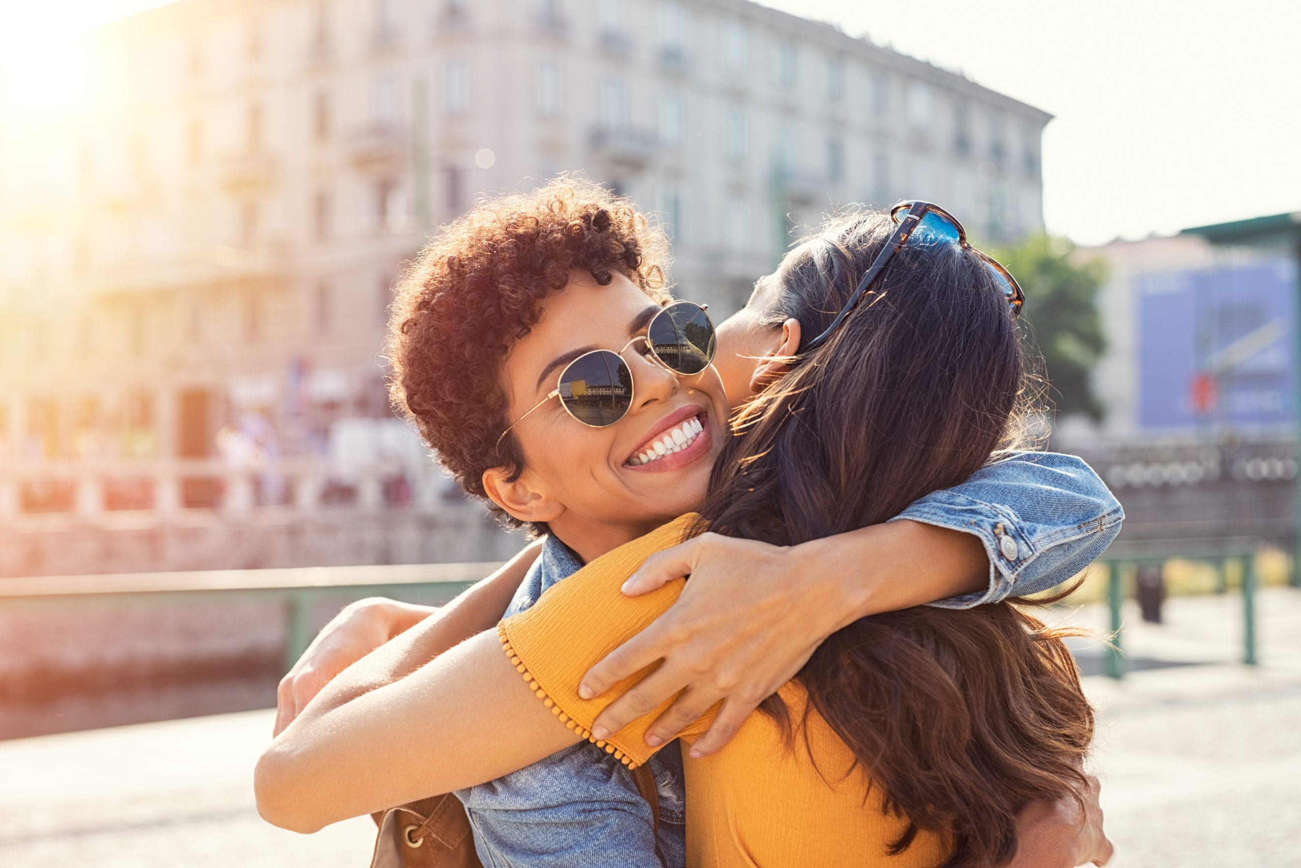 Happy meeting of two friends hugging in the street. Smiling girl