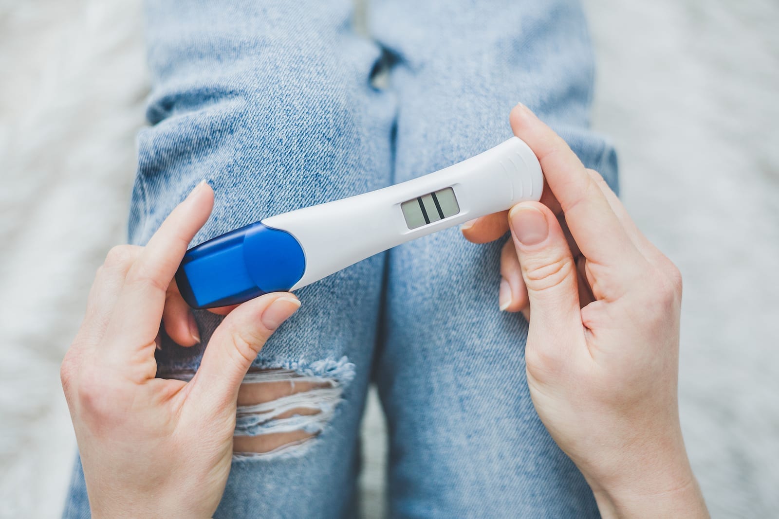 Young Woman Hoding On Jeans And Looking On Positive Pregnancy Te
