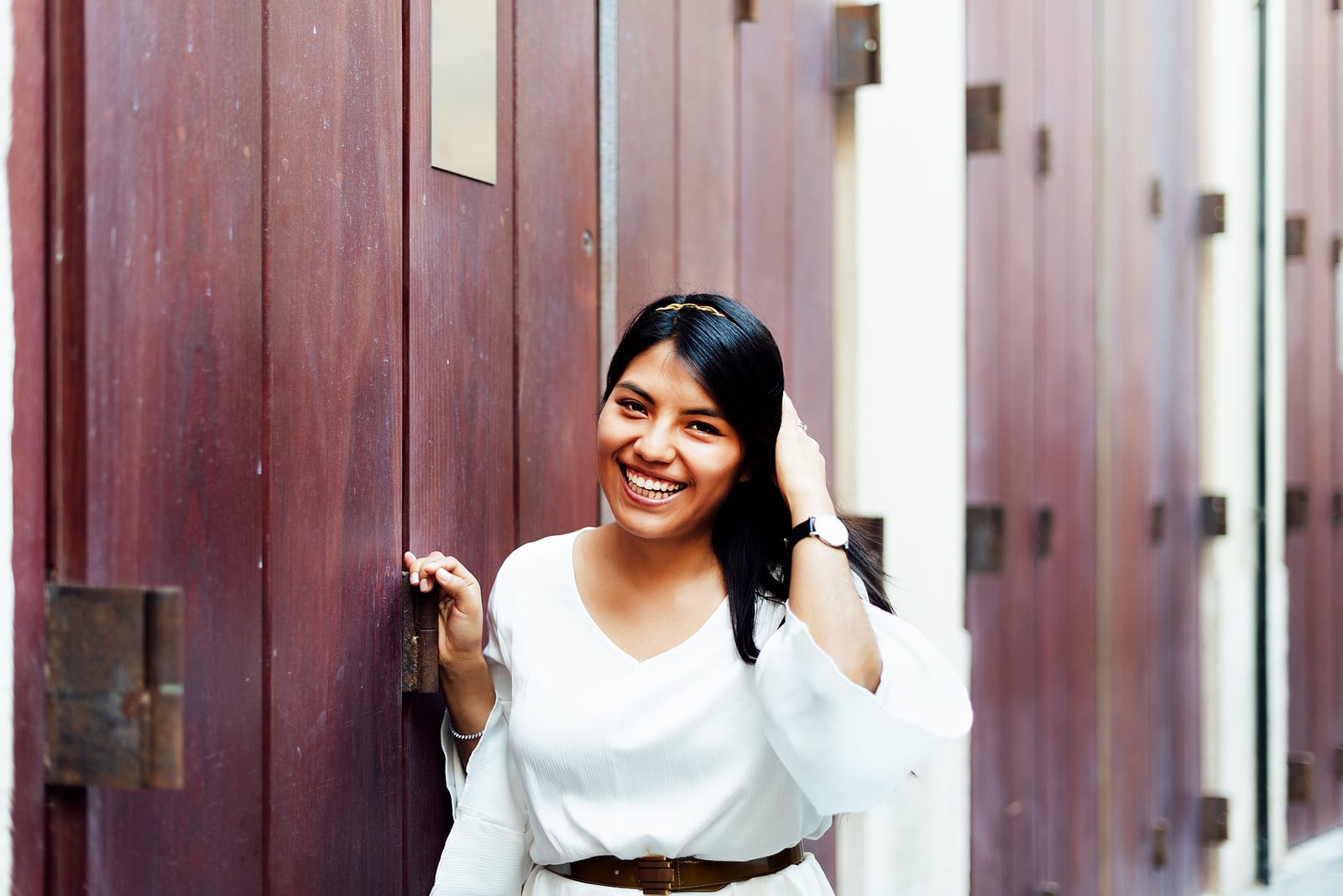 Long-haired Latina Woman In White Dress Smiling At Camera Leanin