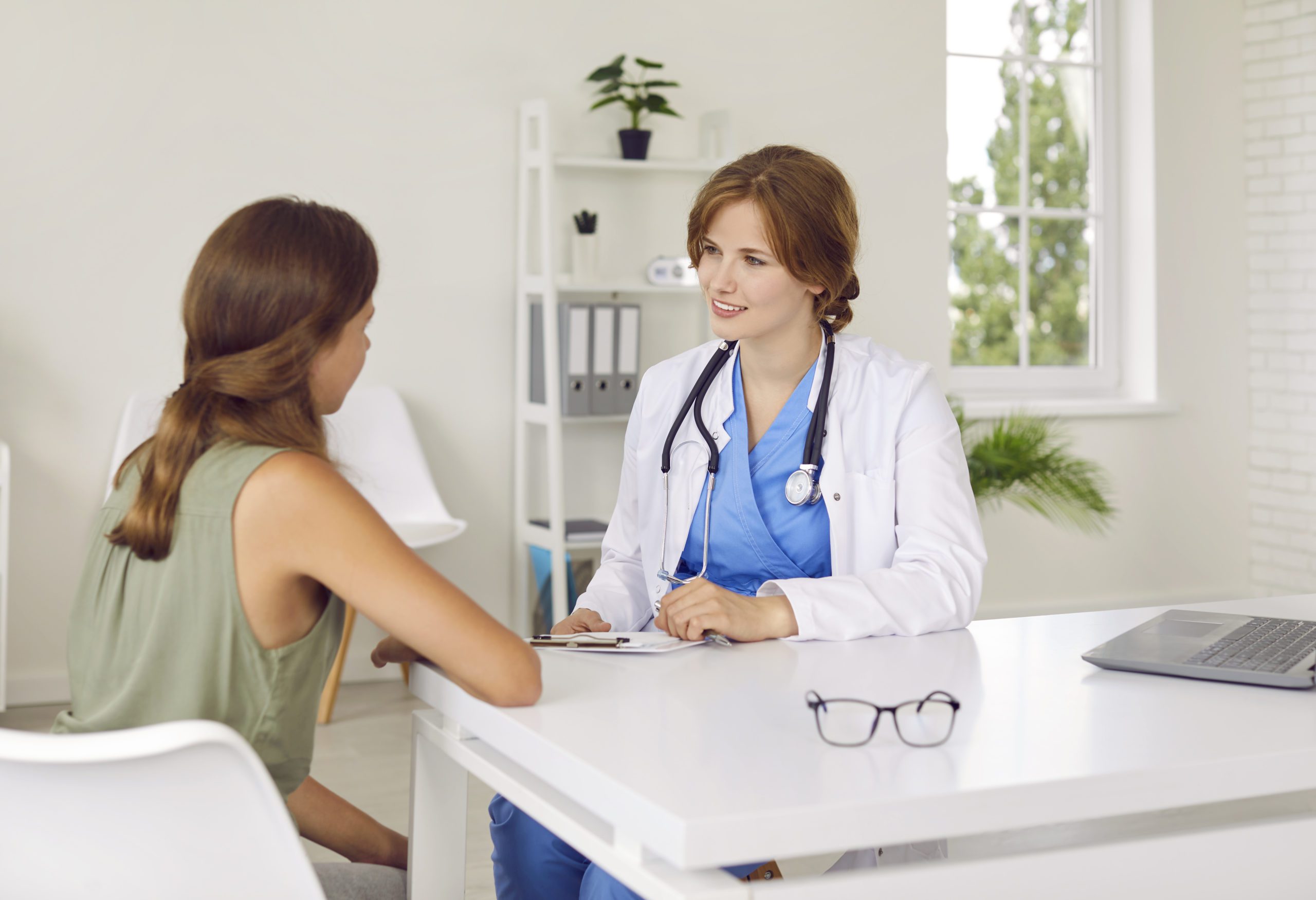 Doctor Pediatrician Talking To Teenage Girl Patient Telling Her