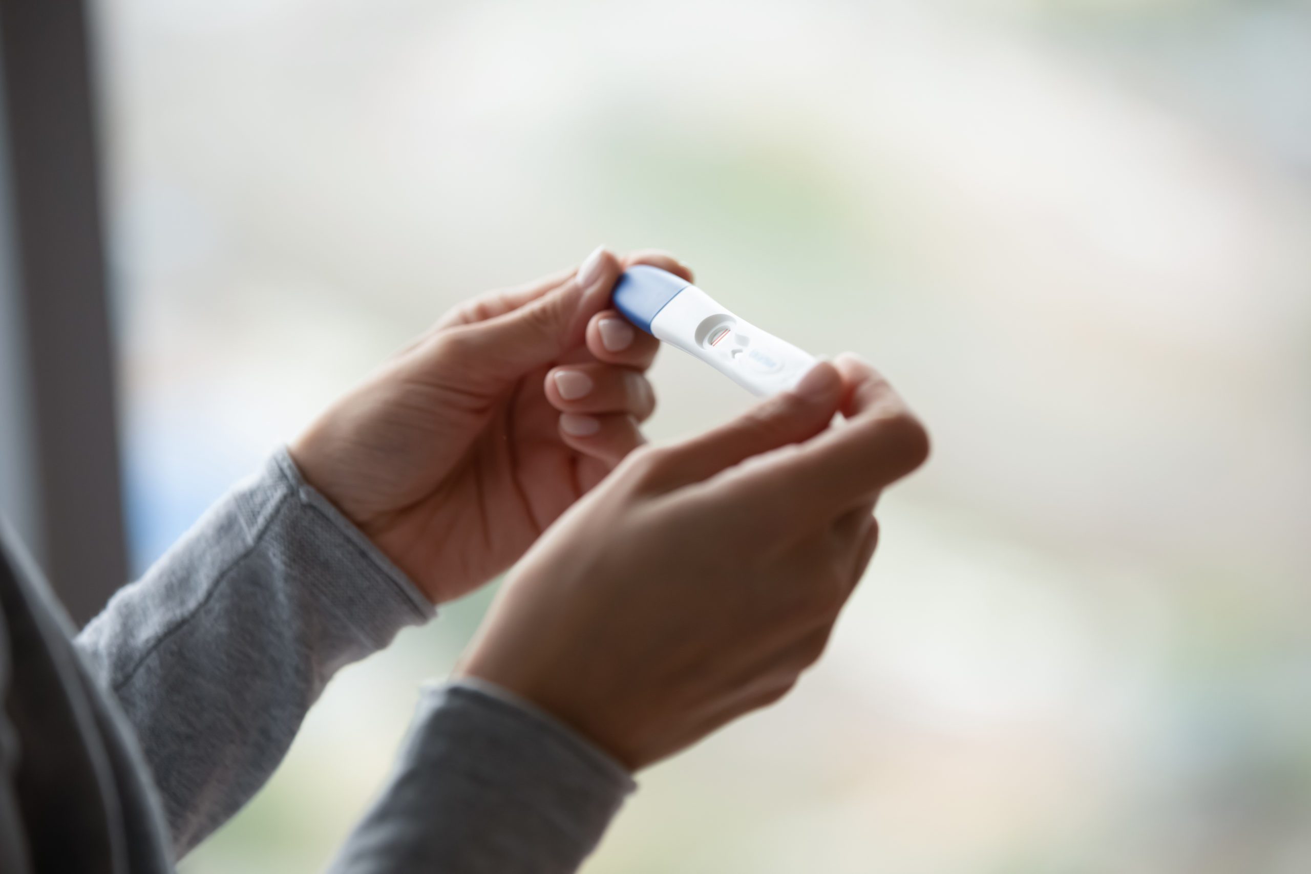 Close Up Of Woman Hands Holding Positive Home Pregnancy Test